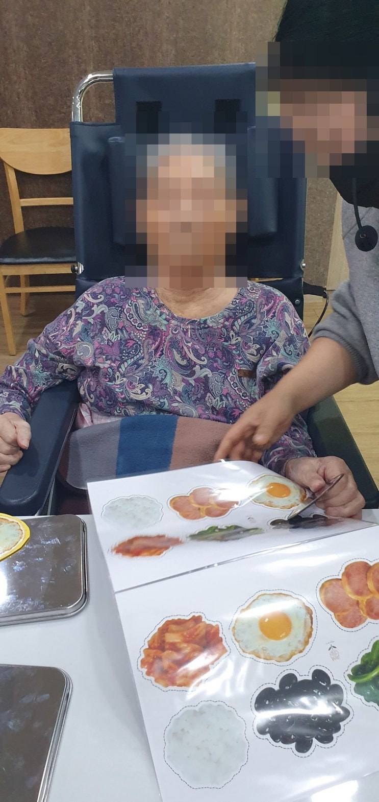 휠체어에 앉아 선생님과 함께 활동하시는 어르신