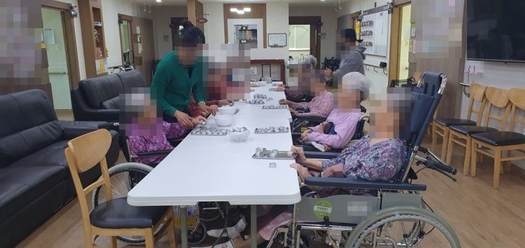 청주 성지요양원 어르신들이 긴 테이블에 둘러앉아 은쟁반 위 틴케이스로 인지프로그램에 참여하는 모습, 얼굴은 개인정보 보호를 위해 모자이크 처리