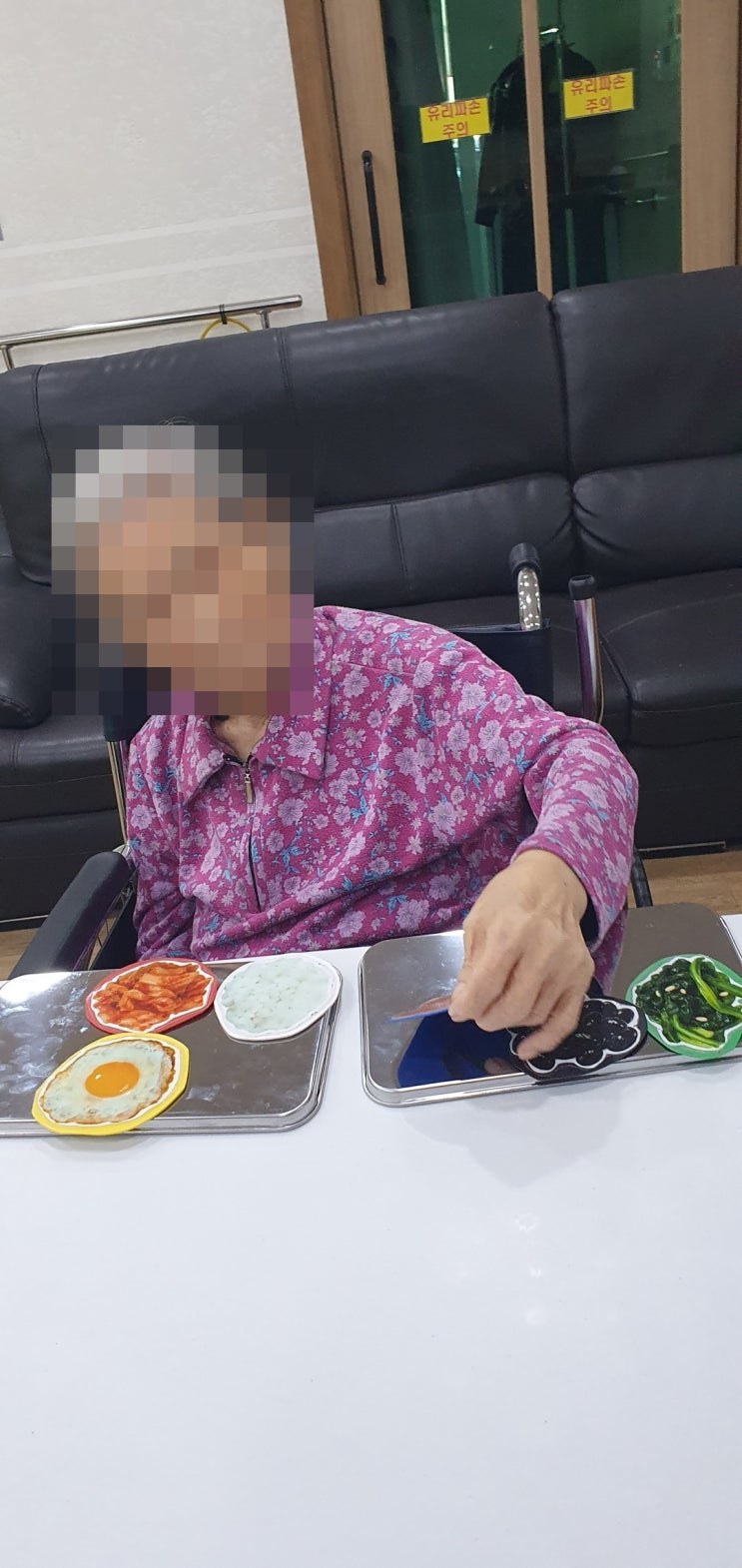 쟁반 위 반찬 모형을 살펴보시는 어르신