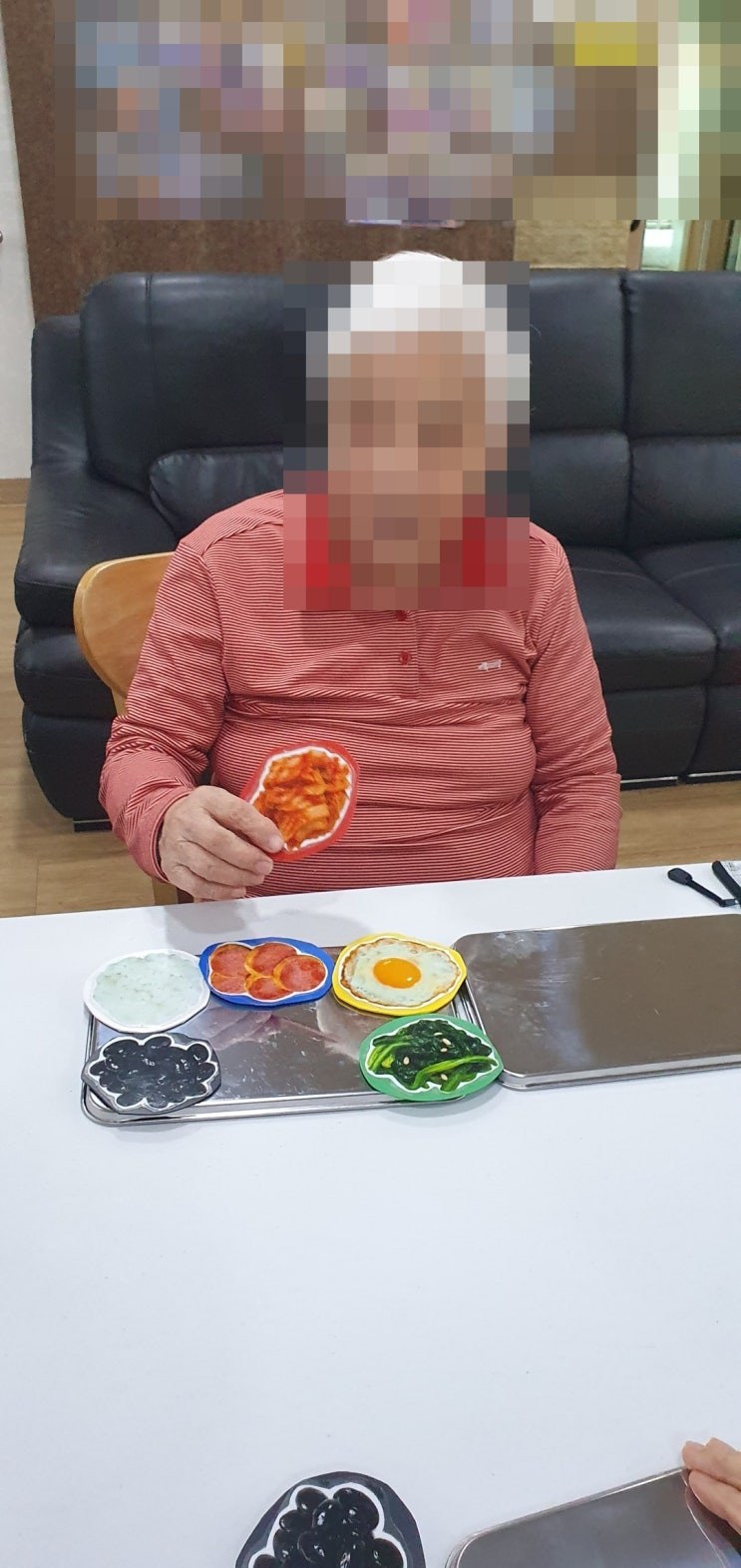김치 모형을 집어 들어 보이시는 어르신