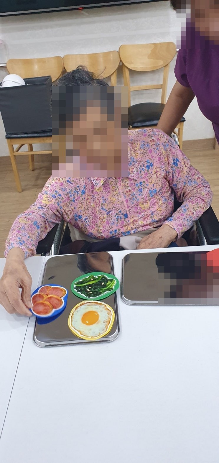 계란 후라이와 김치 모형을 쟁반에 올리시는 어르신