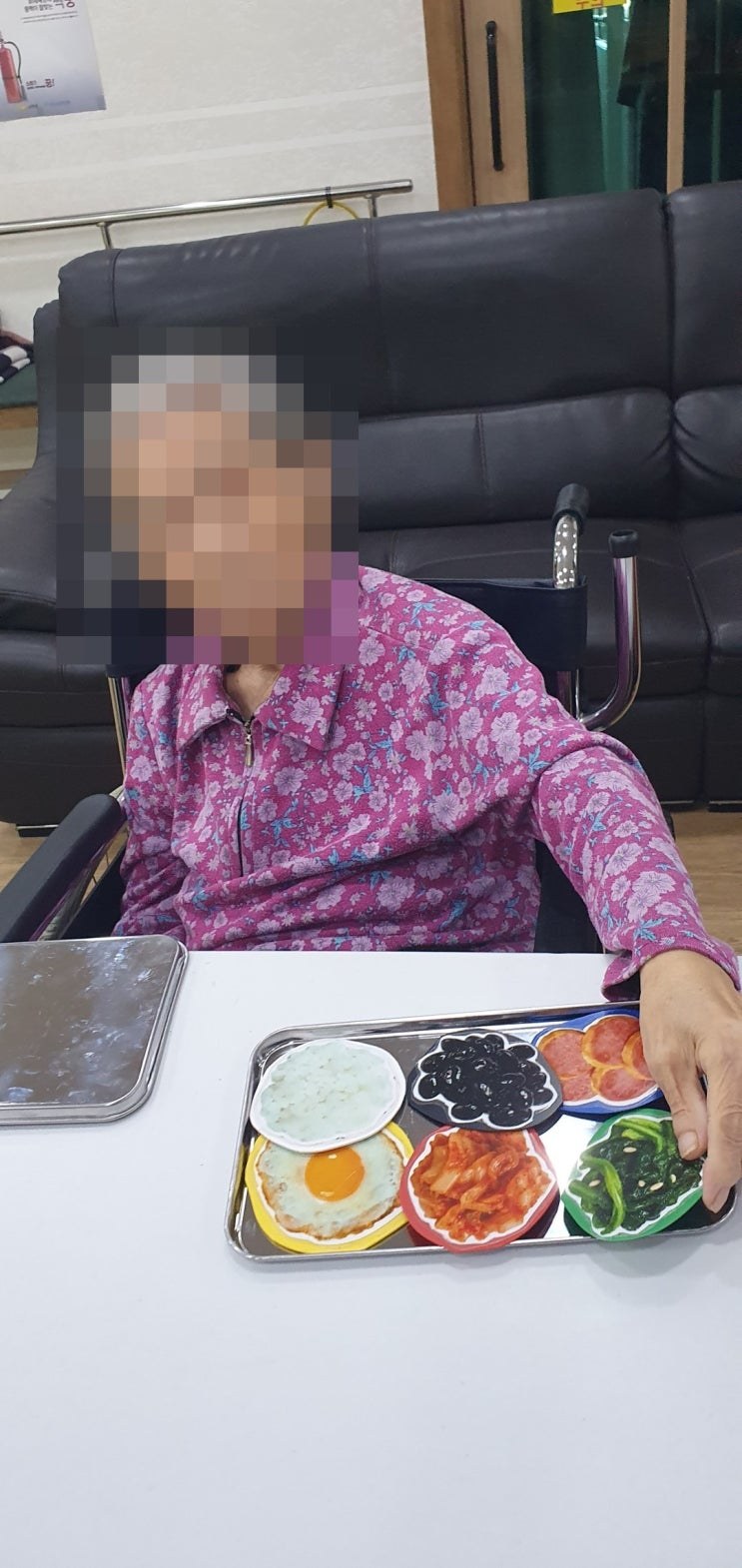 반찬 모형을 담은 쟁반을 정리하시는 어르신