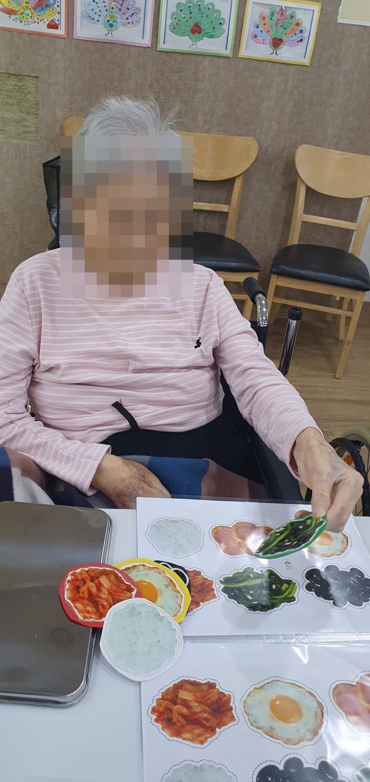 반찬 모형을 워크지에 하나씩 맞춰 보시는 어르신