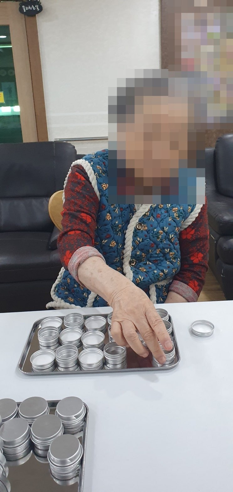 은쟁반 위 틴케이스를 하나씩 나열하시는 어르신