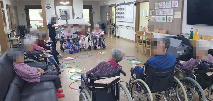 거실 바닥의 훌라후프를 둘러싸고 앉아 주사위 던지기를 하시는 어르신들