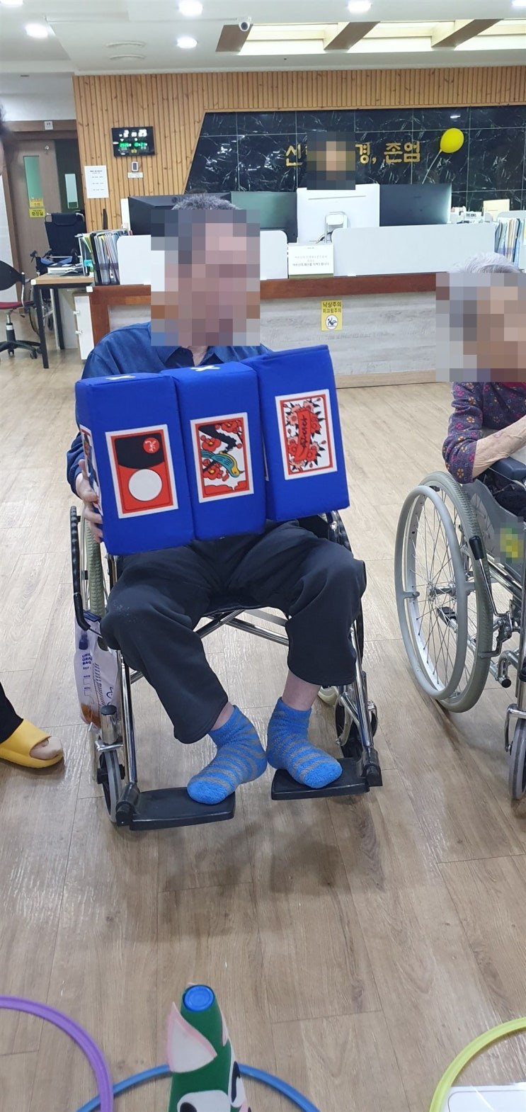 주사위 세 개를 들고 그림을 확인하시는 어르신