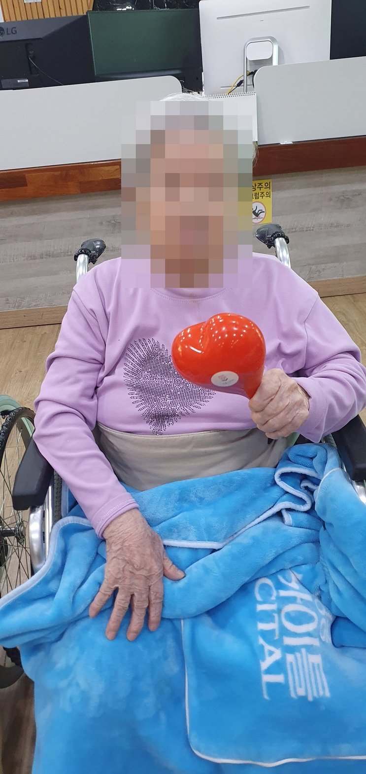 휠체어에 앉아 하트 마라카스를 쥐고 계신 어르신