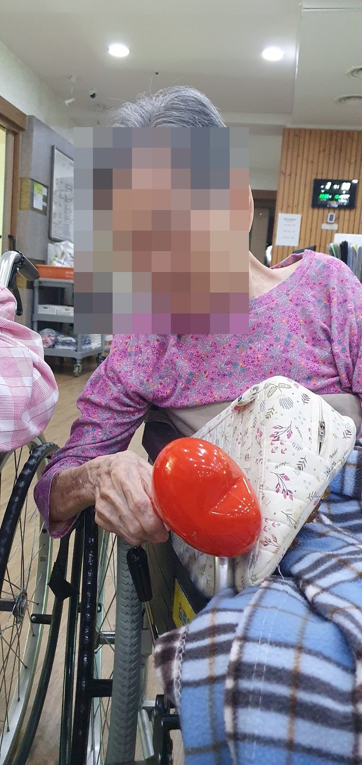 휠체어에 앉아 마라카스를 쥐고 활동하시는 어르신