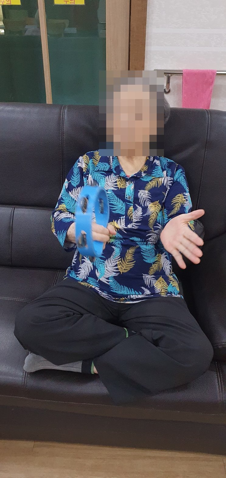 소파에 앉아 파랑 탬버린을 흔드시는 어르신
