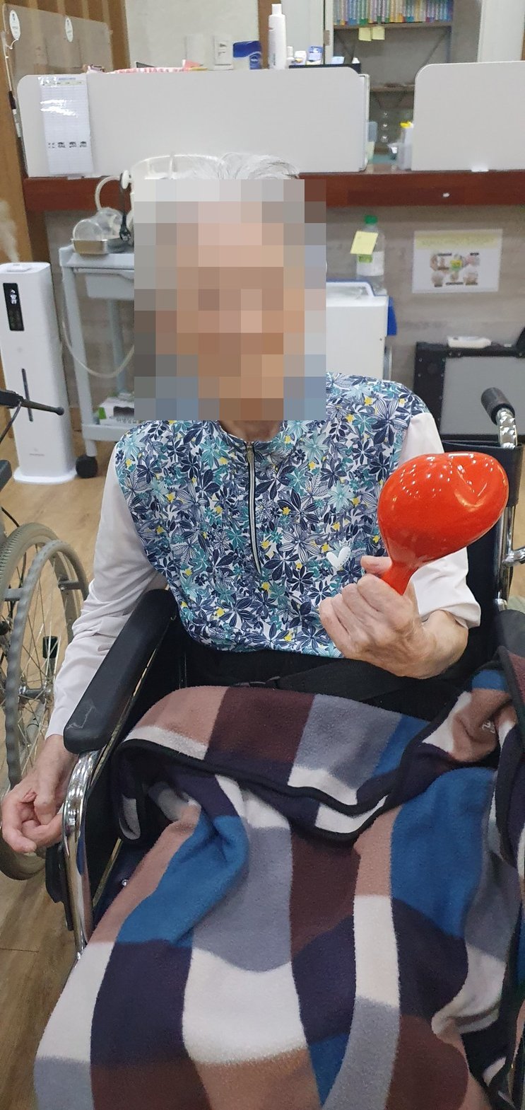 휠체어에 앉아 하트 마라카스를 쥐고 계신 어르신