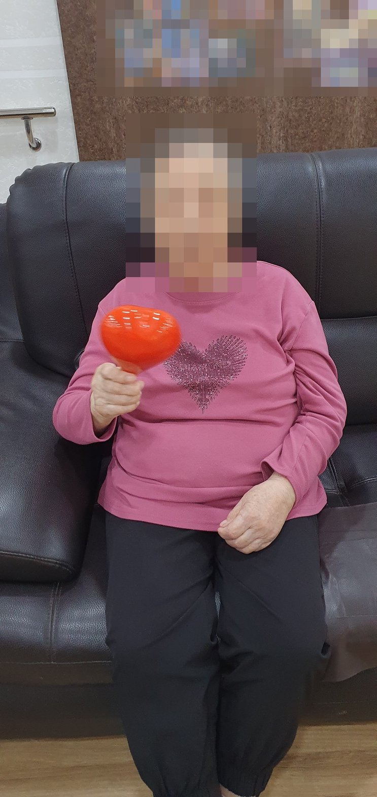 소파에 앉아 하트 마라카스를 흔드시는 어르신