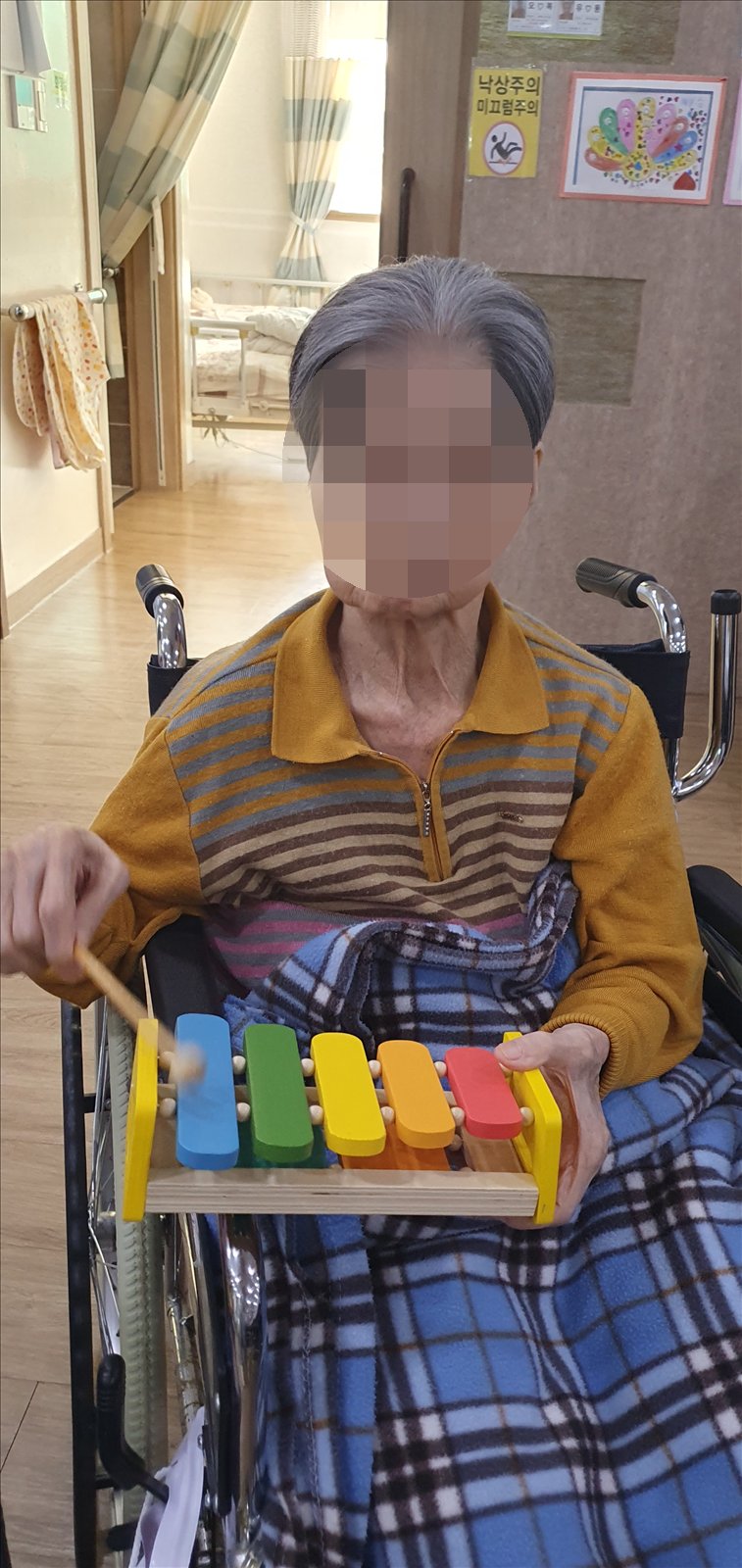 휠체어에 앉아 무릎 위 실로폰을 연주하시는 어르신