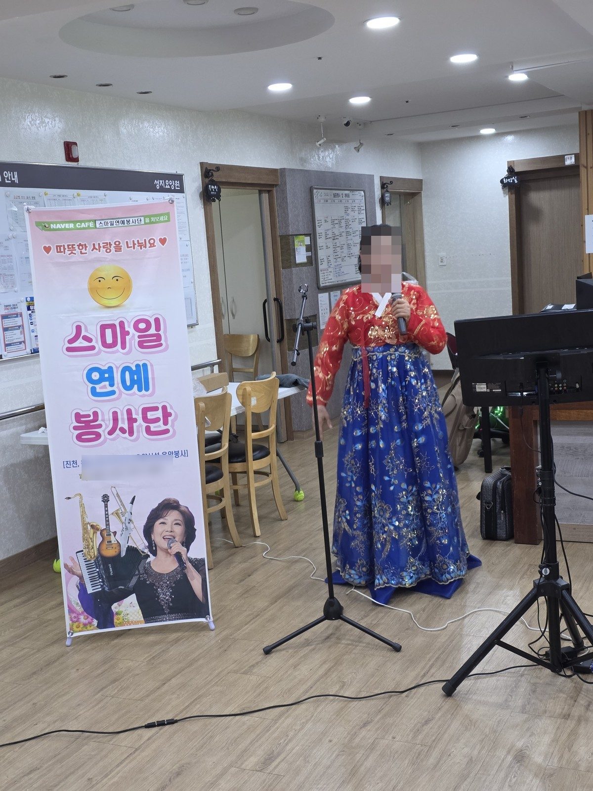 한복을 입고 노래하는 스마일 연예봉사단 단원과 봉사단 현수막